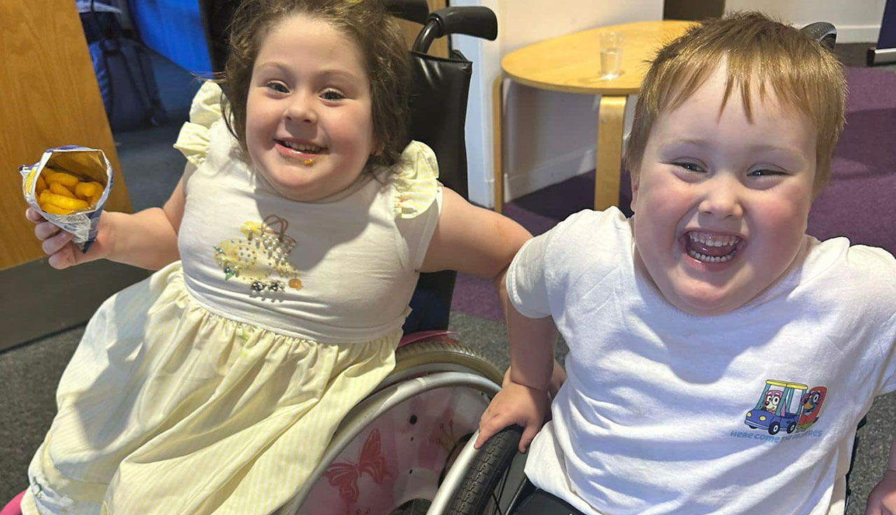 Two children sitting in wheelchairs, smiling